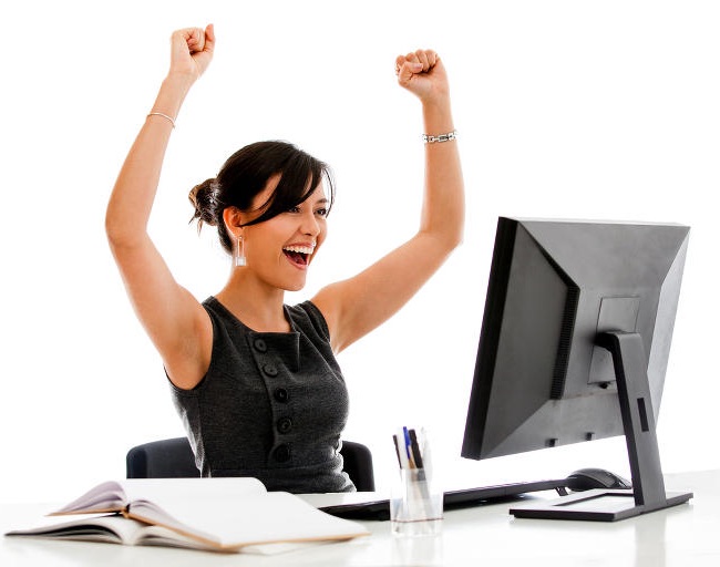 Happy woman cheers at her desktop computer monitor