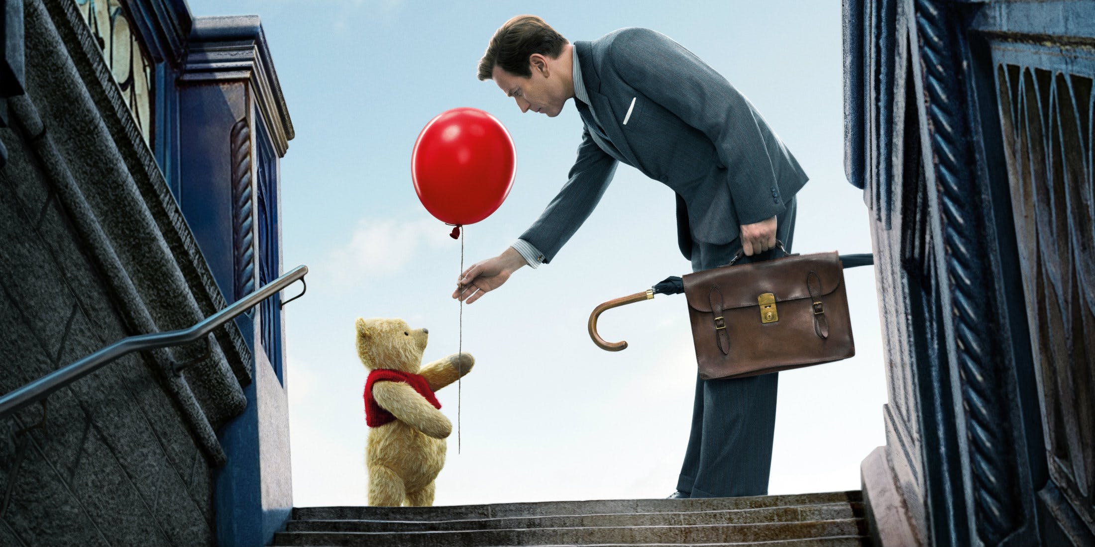 Winnie the Pooh hands Christopher Robin (Ewan McGregor) a red balloon in the poster for the Disney movie